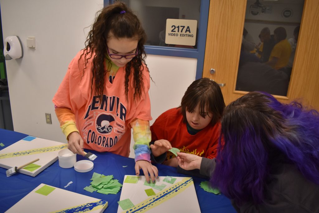 three girls working on an canvas to create a kaleidoscope art installation