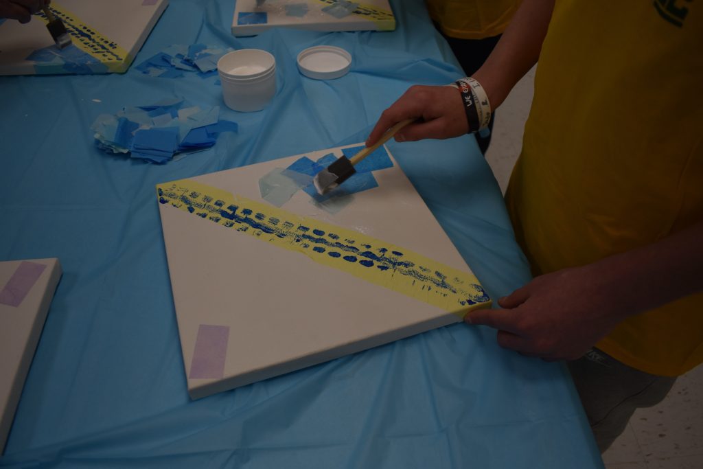 one student painting a square canvas for the kaleidoscope art installation