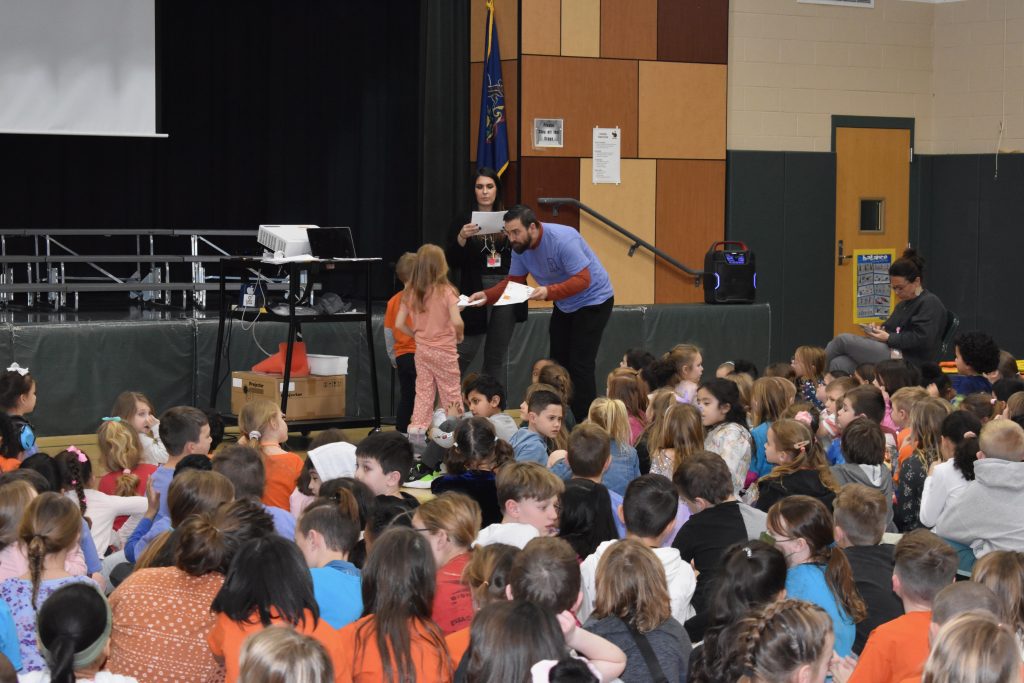 teacher handing out papers to students during the  School-wide Positive Behavior Support assembly