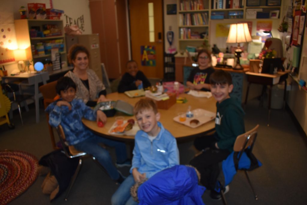 Students and teacher together at a table eating lunch