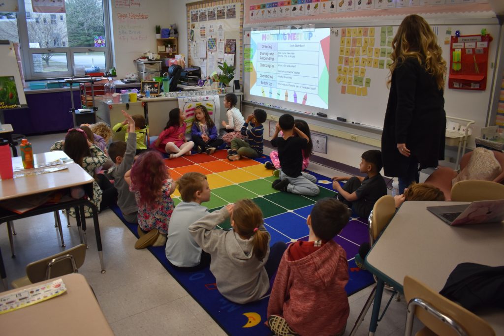 A class of students gathered in a circle listening to a teacher