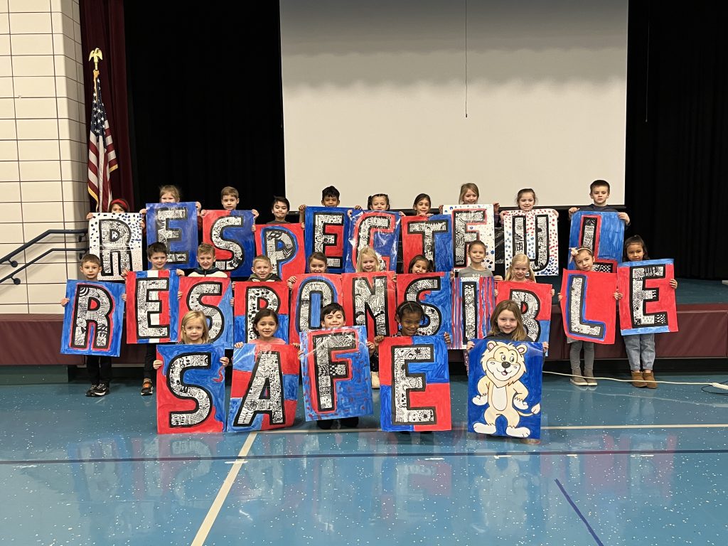 students holding a sign that says "Respectful, Responsible, Safe"